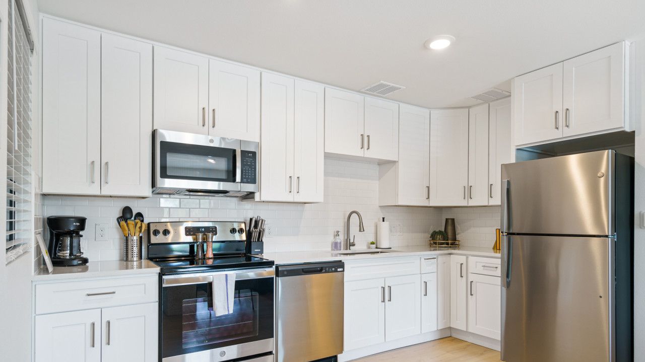 A modern kitchen with white cabinets, stainless steel appliances, and a dishwasher.