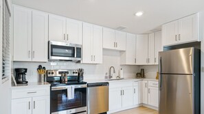 Una cocina moderna con armarios blancos, electrodomésticos de acero inoxidable y lavavajillas.