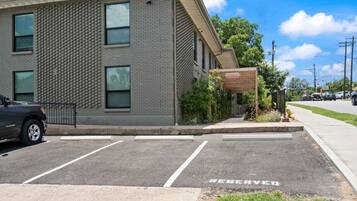 A parking lot with a 'RESERVED' sign, a building with a brick facade, and a covered area with a sign.