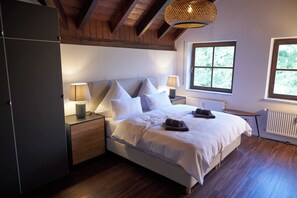 A bedroom with a bed, bedside lamps, a radiator, and a window. - Romantic Penthouse Apartment (Windach)