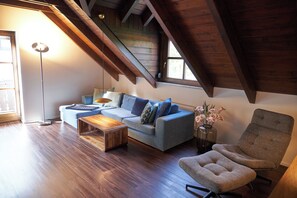 A loft-style living room with a wooden ceiling, a sofa, a coffee table, and a chair. - Romantic Penthouse Apartment (Windach)