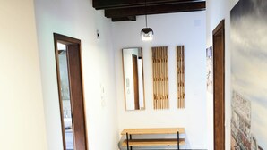 A spacious room with a wooden floor, a bench, and a wall-mounted mirror. - Romantic rooftop apartment (Windach)