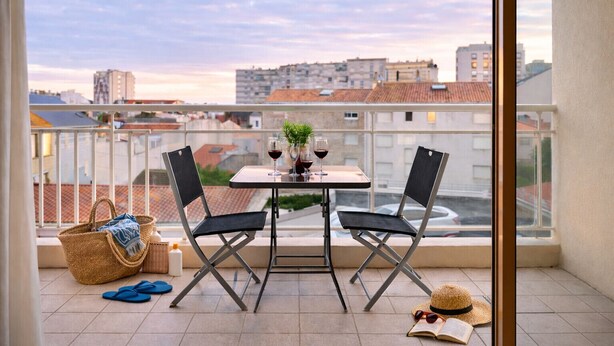 A balcony with a table set for two, two chairs, a small plant, and a basket. - Flat in the heart of Les Sables - 4 people (Les Sables-d´Olonne)