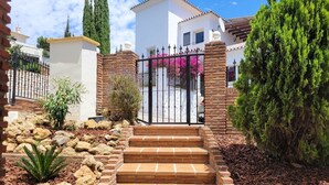 Il s’agit d’une propriété résidentielle dotée d’une entrée sécurisée par un portail, d’un escalier en pierre et d’une grande variété de plantes.