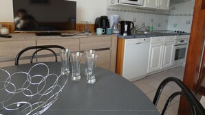 Eine Küche mit Fernseher, Mikrowelle, Kaffeemaschine und einem Esstisch mit Gläsern.