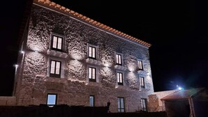 A stone building with multiple windows and a balcony, illuminated at night. - Masseria Torre Saracena (Favara)