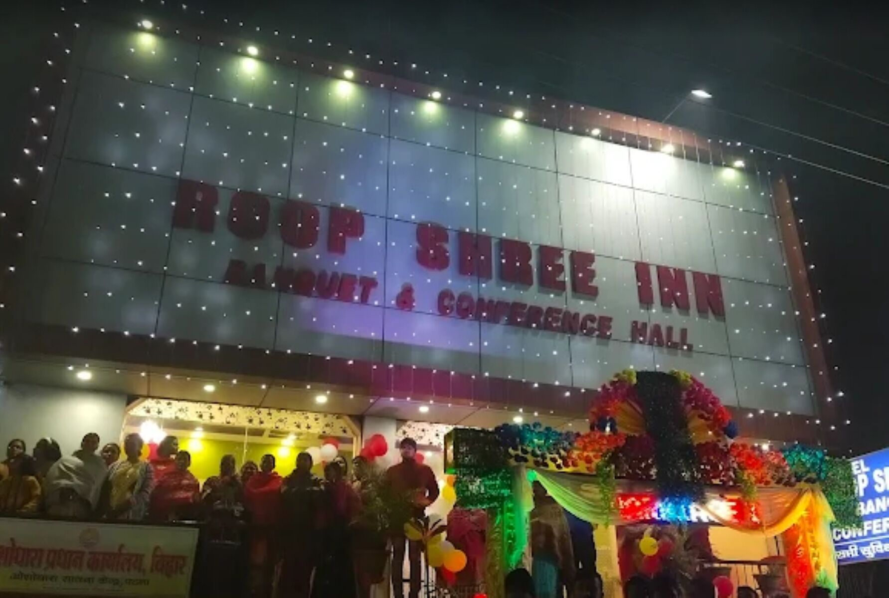 Un hôtel avec une grande enseigne indiquant « BOOP SHREE INN » et « SALLE DE BANQUET ET DE CONFÉRENCE ».