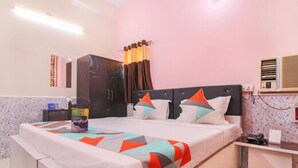 A hotel room with a bed, a desk, a wardrobe, and an air conditioning unit. - Hotel Roop Shree Inn By GRB (Patna)