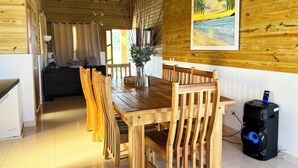 A wooden dining area with a table, chairs, and a painting of a beach scene.