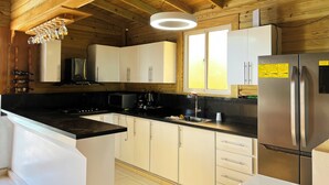 A modern kitchen with wooden beams, white cabinets, stainless steel appliances, and a black countertop.