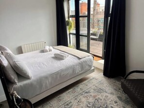 Ein Hotelzimmer mit einem Bett, einem Sessel und Blick ins Freie.