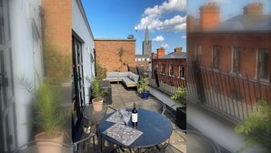 A courtyard with a round table, potted plants, and a brick building in the background. - 2 Bed City Centre Penthouse with Cathedral Views (Dublin)