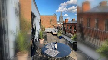 A courtyard with a round table, potted plants, and a brick building in the background.
