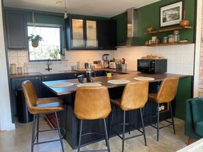 Une cuisine moderne dotée d’un îlot central, de tabourets de bar et d’un four à micro-ondes.