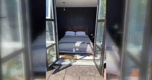 A bedroom with a bed, a window, and a door.