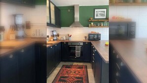 Une cuisine avec des meubles de rangement de couleur sombre, un four à micro-ondes, un grille-pain et une machine à café.