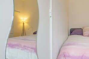 A bedroom with a bed, a bedside table, a lamp, and a wall-mounted light.