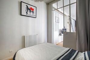 Un dormitorio con cama, un radiador, una ventana y una puerta que da a otra habitación.