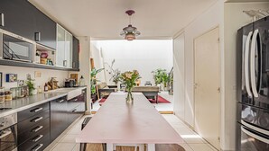 A modern kitchen with a central island, stainless steel appliances, and a view to a living area. - Stunning 3BD Industrial-style Maisonette—Villette (Paris)