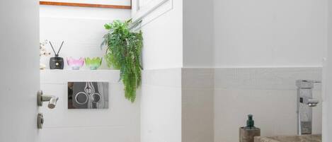 A compact bathroom with a white toilet, a small sink with a stone countertop, and framed artwork on the walls.