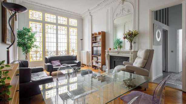 A spacious living room with a glass coffee table, leather sofas, a fireplace, and a bookshelf. - Beautiful 1BD Apartment—Porte Dauphine (Paris)