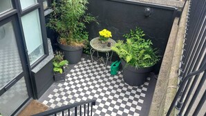 A small balcony with a checkered floor, potted plants, and a metal table. - Cozy Basement Gem in Top Area (Dublin)