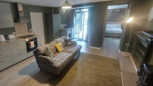 A compact living space with a kitchenette, a sofa with cushions, and a small dining area. - Cozy Basement Gem in Top Area (Dublin)
