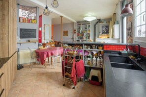 A kitchen with a dining table, a sink, and a variety of kitchen utensils and appliances. - Artistic Parisian Home for 5 in Charonne (Paris)
