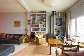 A cozy living room with a fireplace, bookshelves, a sofa, and a dining area.
