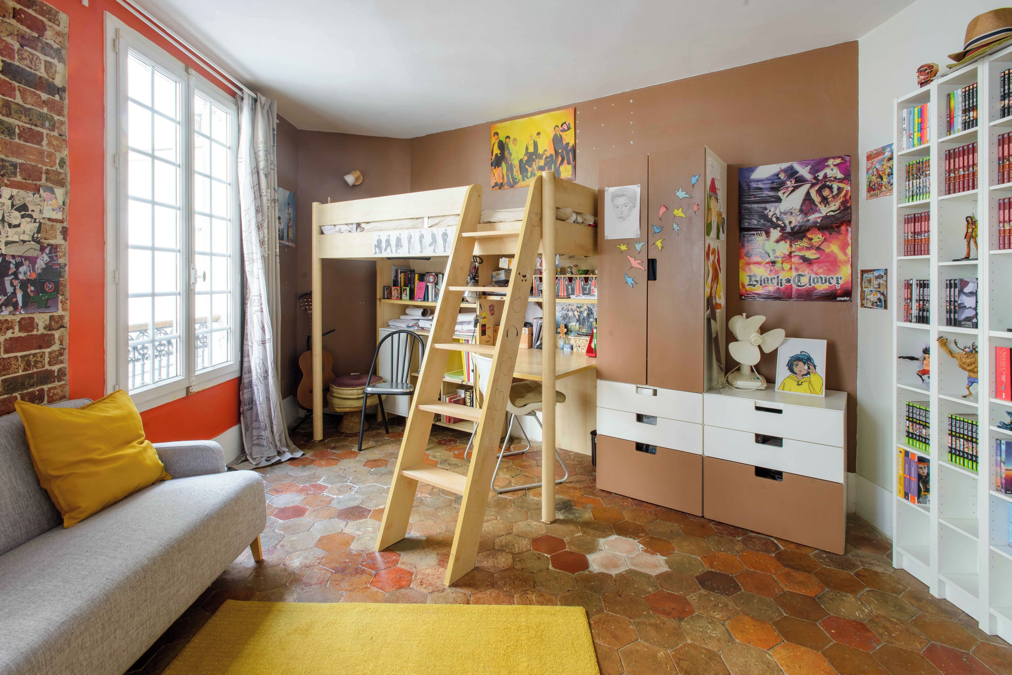 Una habitación con literas, un escritorio, una estantería y una ventana con cortinas.
