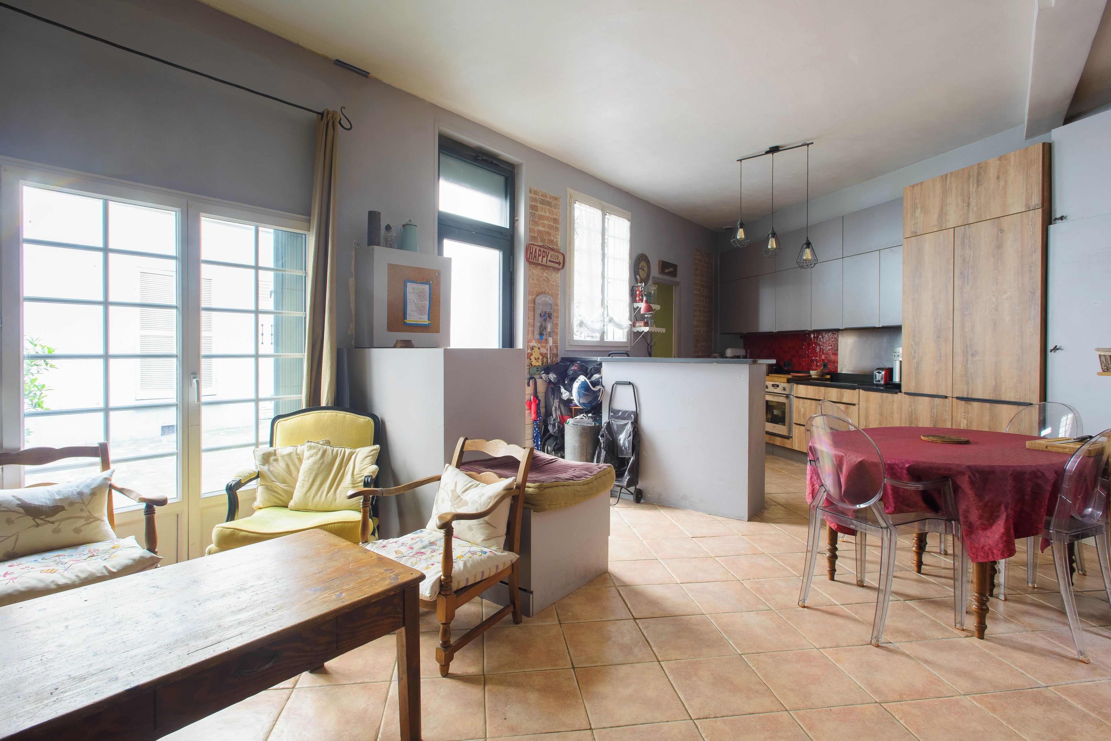 A spacious living area with a dining table, chairs, a sofa, and a kitchen in the background.
