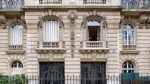 Une façade de style classique, ornée de détails architecturaux raffinés, notamment des colonnes, des arcs et des moulures décoratives.