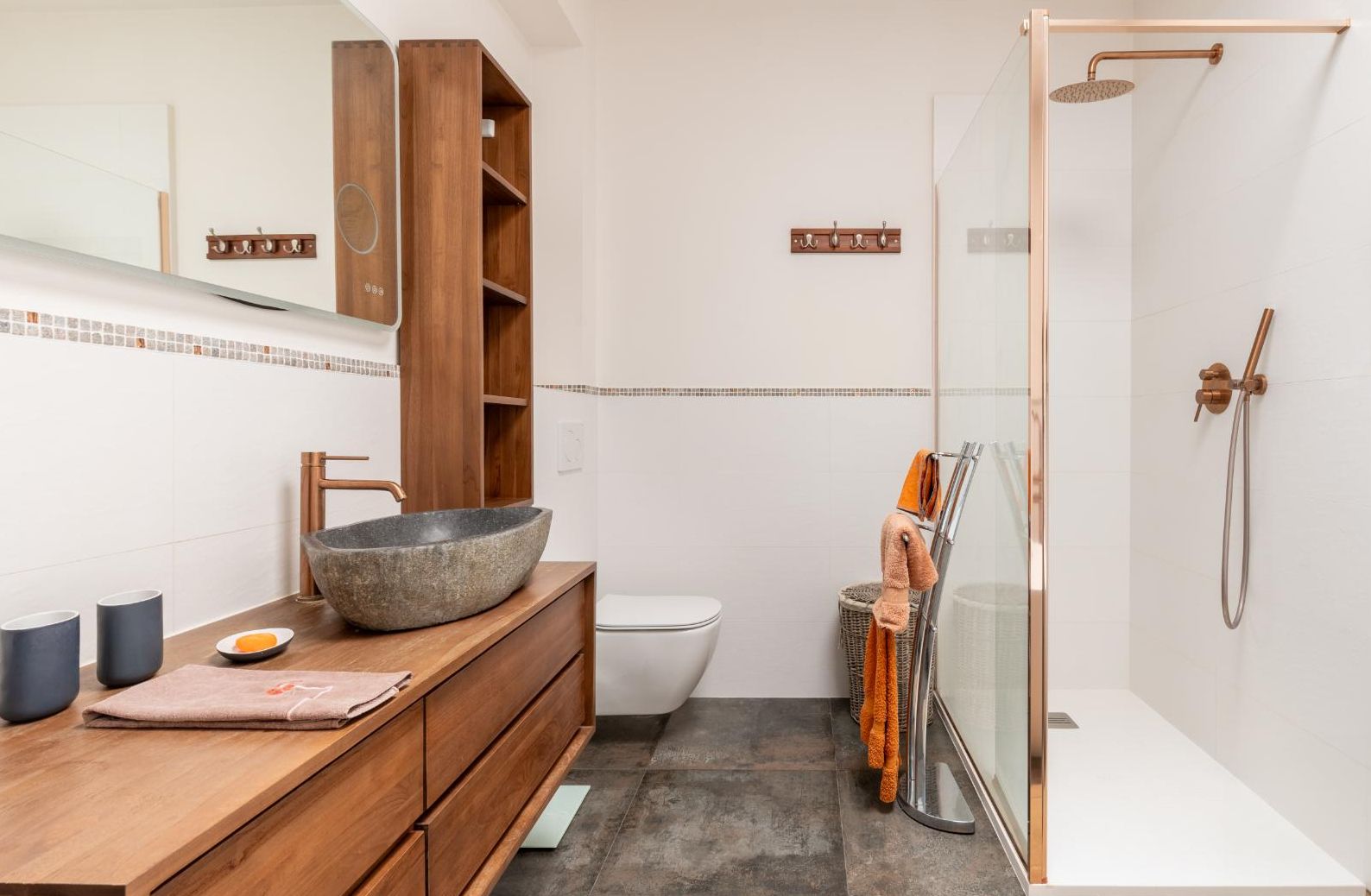 Een badkamer met een houten wastafelmeubel, een ruime wastafel, een toilet en een douchecabine met glazen wanden.
