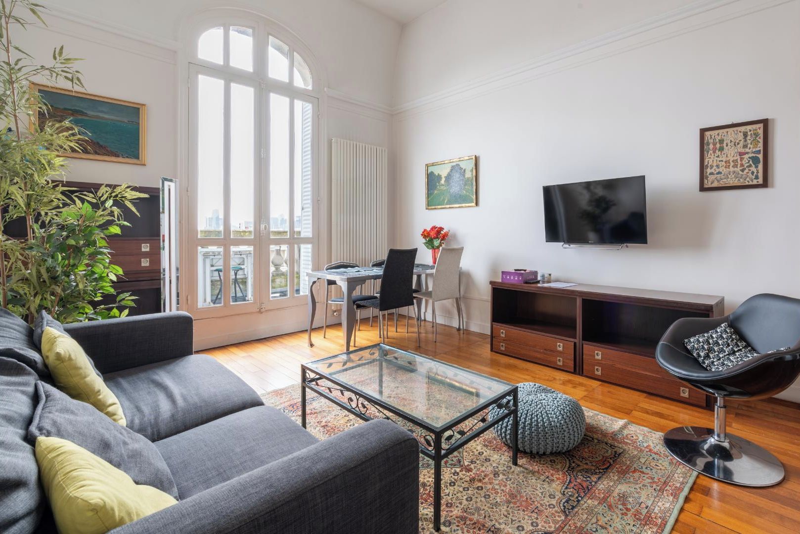 Een moderne woonkamer met een bank, salontafel, televisie en een eethoek.