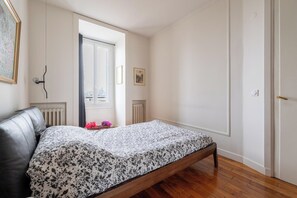 Une chambre à coucher avec un lit, un radiateur, une fenêtre et une porte.