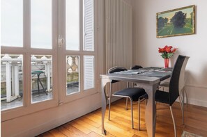 Un coin repas avec une table et des chaises, une fenêtre avec des volets et un tableau accroché au mur.