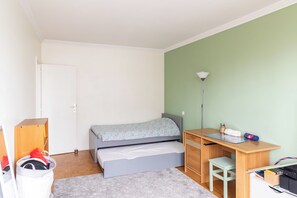 Une chambre à coucher avec un lit, un bureau, une chaise et une petite table sur laquelle se trouvent divers objets.
