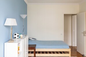 A bedroom with a single bed, a desk with a lamp, a soccer ball, and a small chair. - Bright 3BD Family Flat w/ Balcony—Auteuil (Paris)