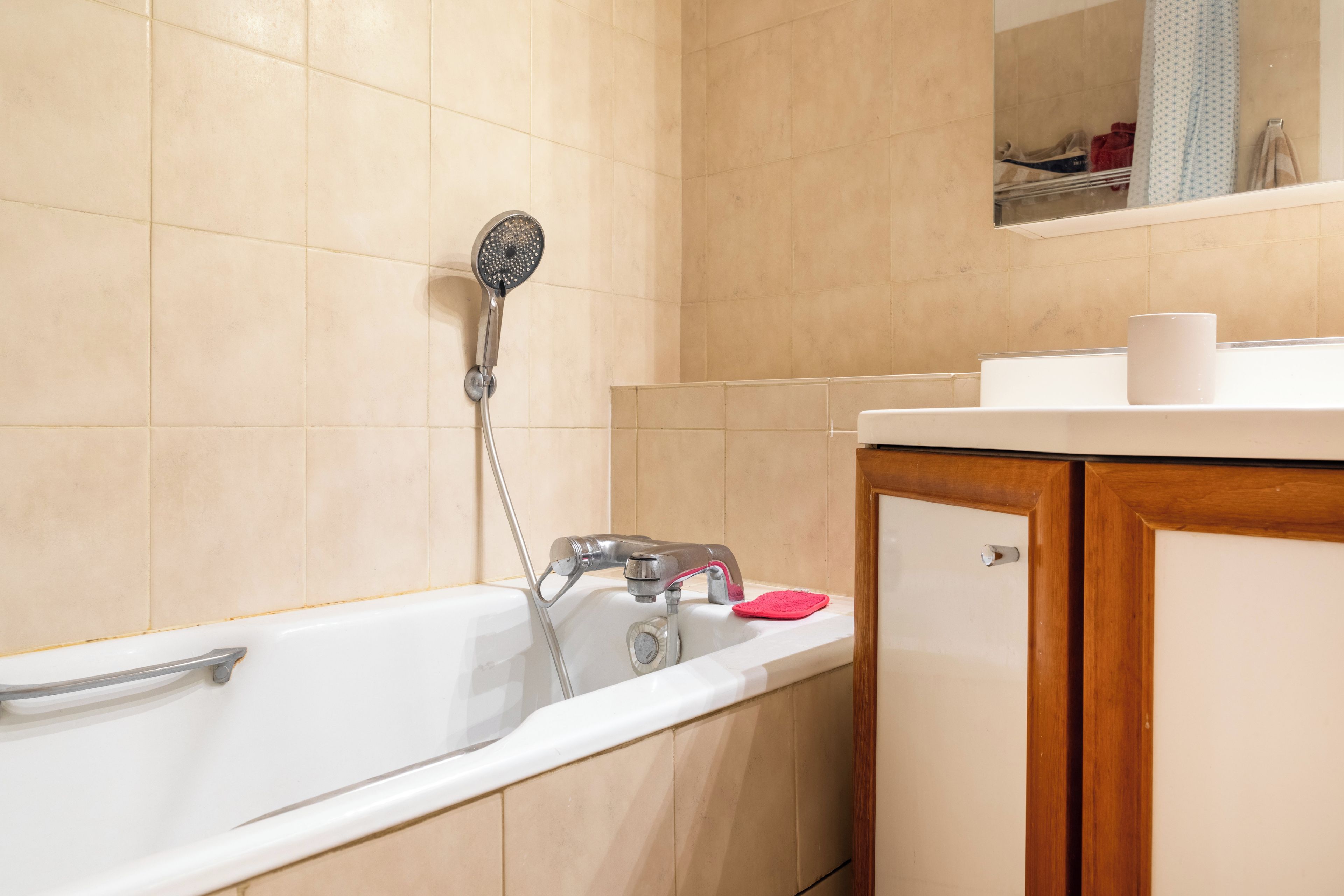 Ein Badezimmer mit einer weißen Badewanne, einer Duschbrause, einem Waschbecken und einem Spiegel über dem Waschbecken.