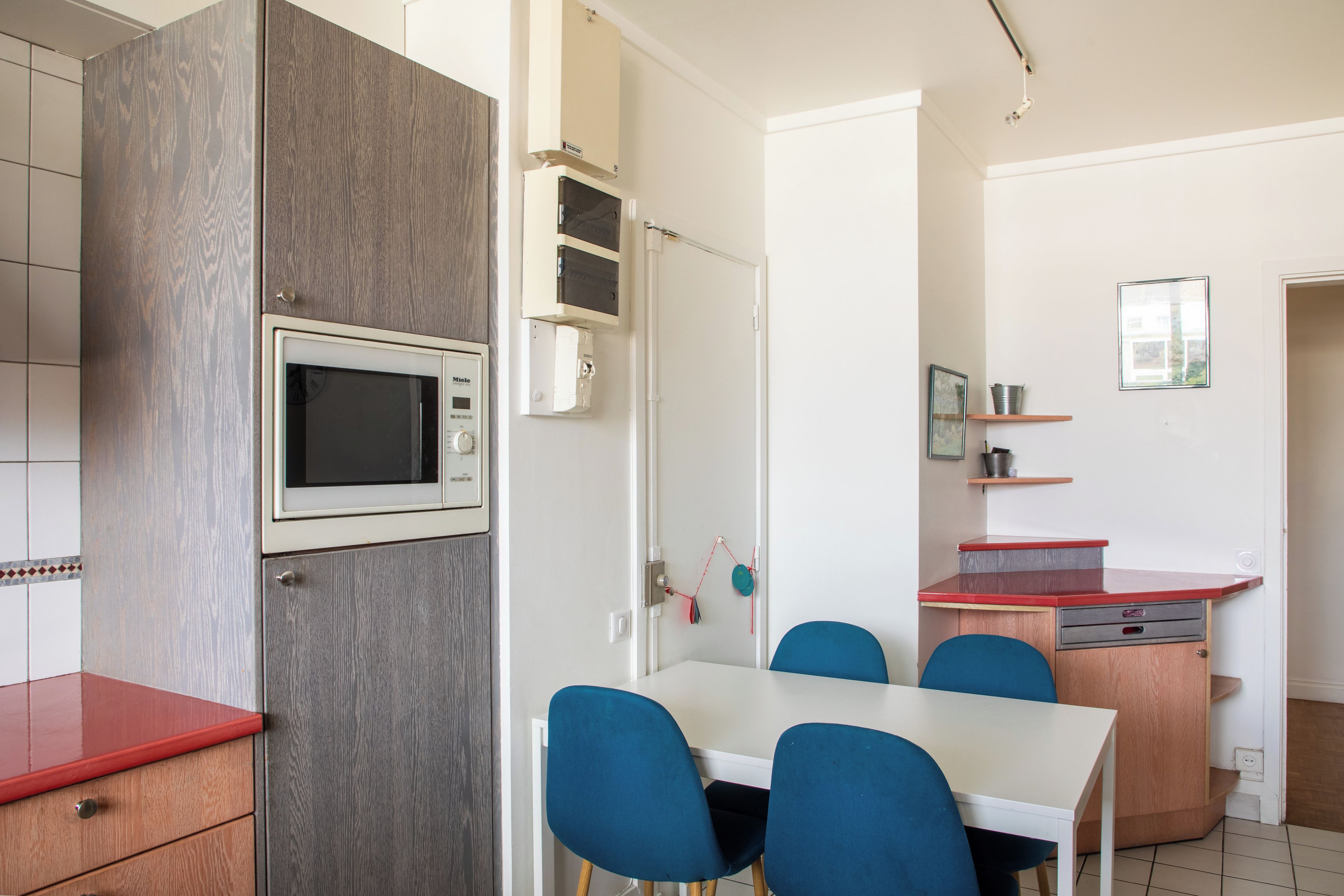 A compact kitchen with a microwave, a wooden cabinet, and a dining area with a table and chairs.