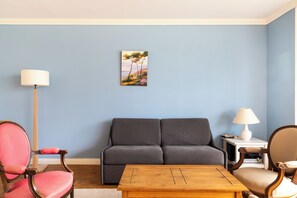 A living room with a sofa, two chairs, a coffee table, a lamp, and a painting on the wall. - Bright 3BD Family Flat w/ Balcony—Auteuil (Paris)
