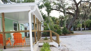 A house with a porch, wooden railing, and orange chairs.