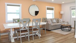 A modern living room with a dining table, grey chairs, a sofa, and a round coffee table.