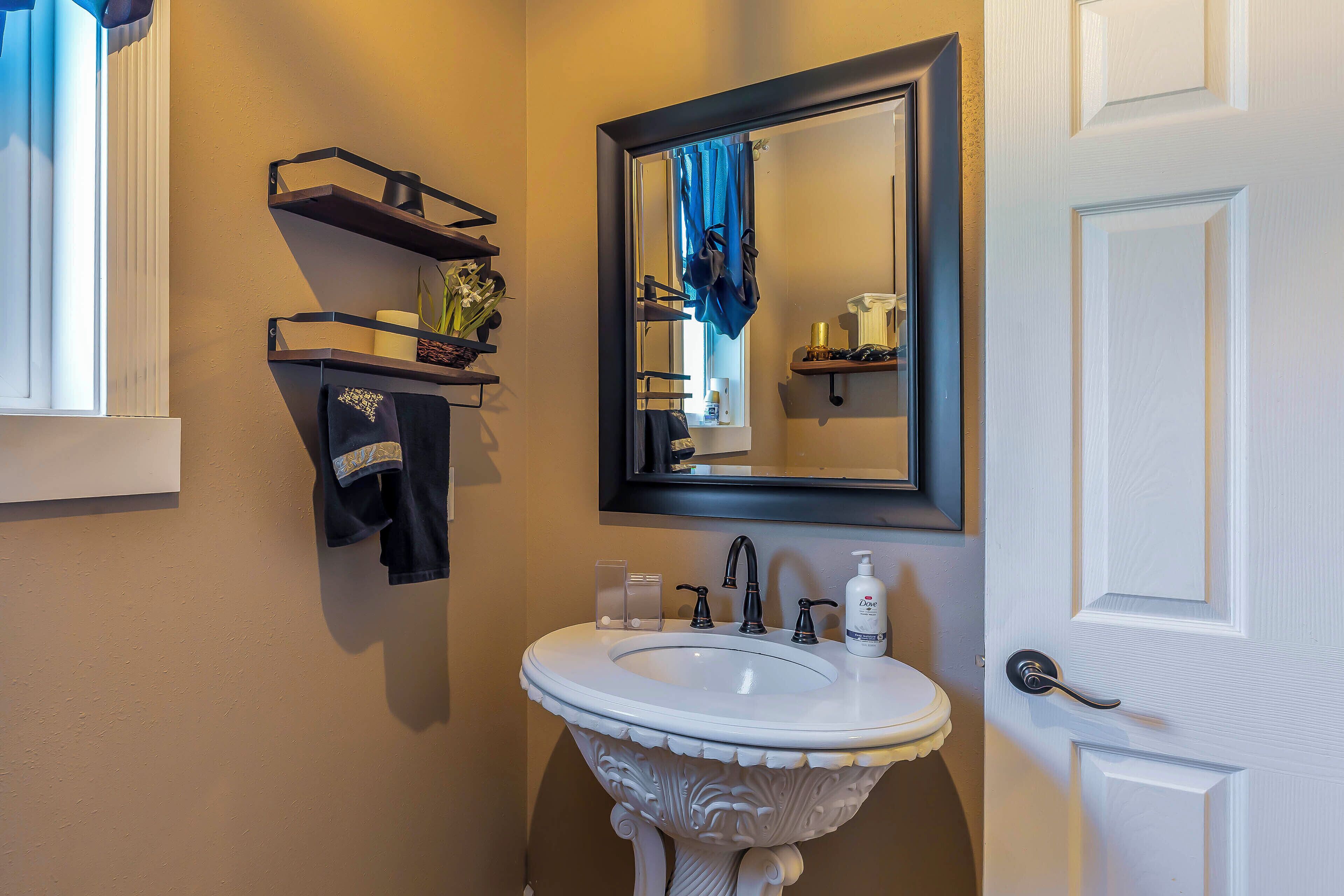 A bathroom with a white sink, a mirror, a towel rack, and a door.