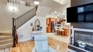 Ein geräumiges Wohnzimmer mit Treppe, Kamin, Essbereich und Küche.