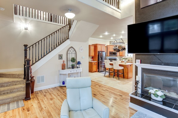 A spacious living area with a staircase, a fireplace, a dining area, and a kitchen. - Backyard Resort,hottub,heated Pool,firepit,uofo 6m (Eugene)