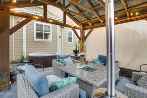 An outdoor patio with wicker furniture, a hot tub, and string lights. - Heated Pool, Hot Tub & Fire Pit in Ruby Park (Eugene)