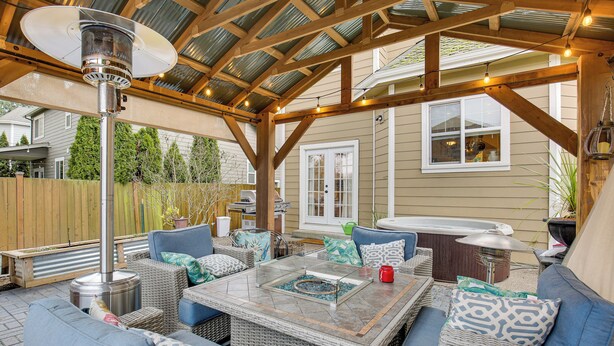 Eine Terrasse im Freien mit Korbmöbeln, einem Tisch mit Glasplatte und einem Terrassenheizer.