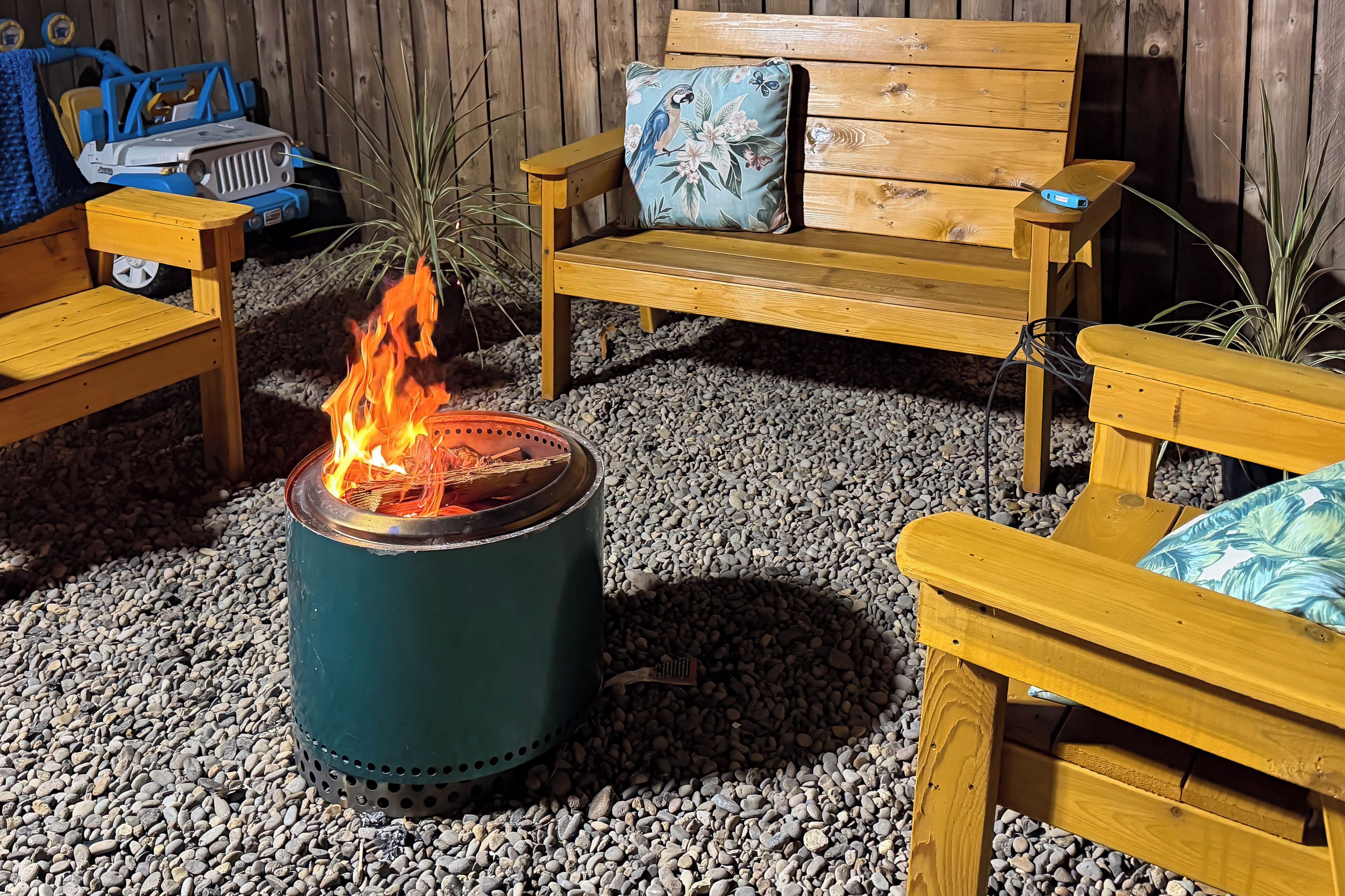 A wooden outdoor seating area with a fire pit in the center.