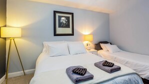 Hotellihuone, jossa on kaksi sänkyä, seinällä kehystetty taulu ja kaksi yöpöytälamppua.